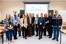 fot. Sebastian Jętczak/UG Zdjęcie grupowe jedenastu osób stojących rzędem przed ekranem projekcyjnym w sali konferencyjnej. Wszyscy uśmiechają się do aparatu.