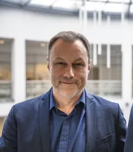 Mężczyzna w granatowej marynarce i granatowej koszuli na tle rotundy WNS