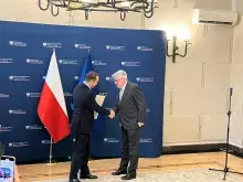 Dwóch mężczyzn stojących na granatowej ściance z napisem "ministerstwo spraw zagranicznych"