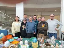 8 osób stojących za stołem z prezentowanymi stroikami