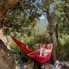 Zdjęcie dwóch młodych mężczyzn w hamakach wśród śródziemnomorskich drzew