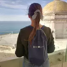 Ujęcie studentki z tyłu, w tle budynek z kopułą, wybrzeże i morze